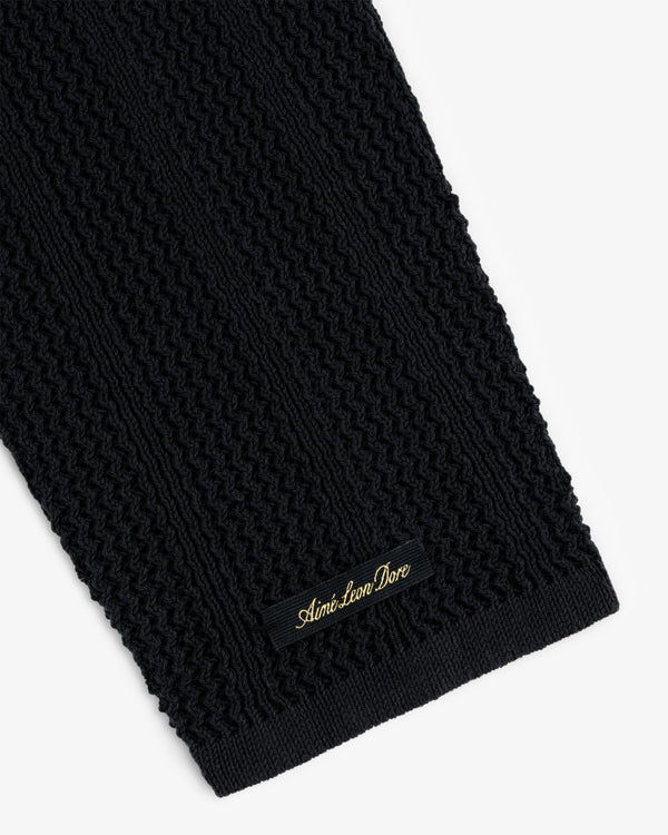 Close-up of a black textured Racking Stitch Crewneck Sweater with a small Aimé Leon Dore label sewn near the edge.