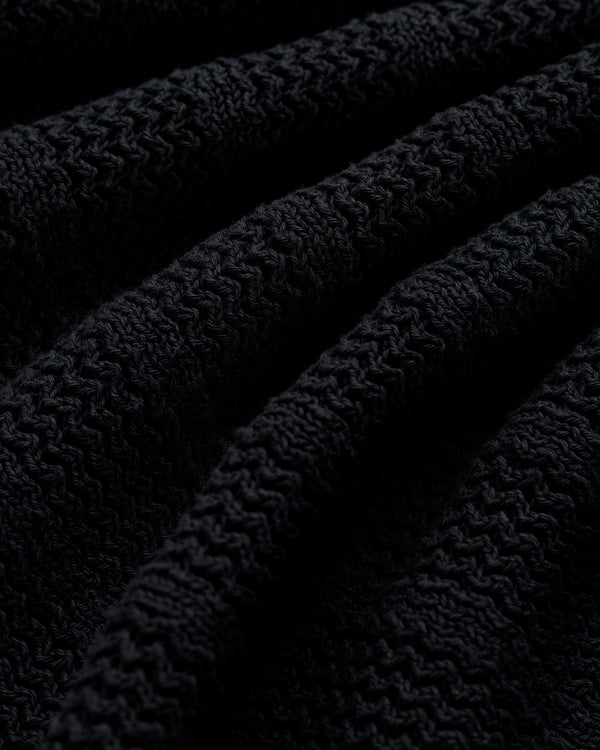 Close-up of the Racking Stitch Crewneck Sweater in black, showing its ribbed, textured knit and gentle folds.