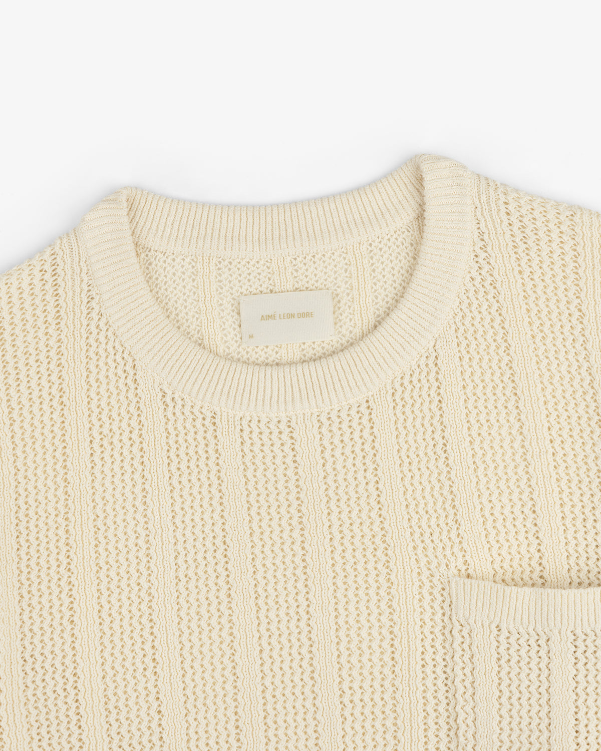 Racking Stitch Crewneck Sweater in beige with ribbed collar and chest pocket, shown flat on a white background.