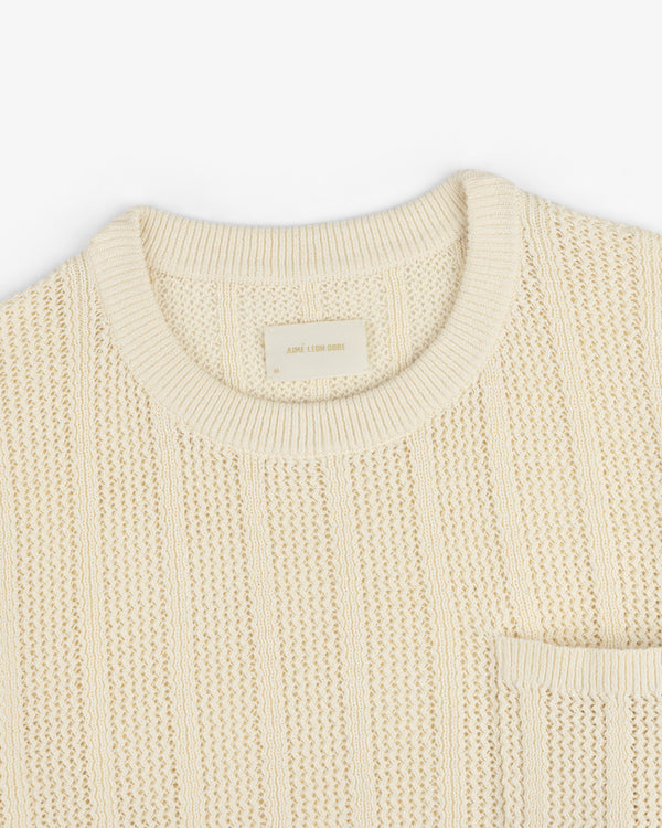 Racking Stitch Crewneck Sweater in beige with ribbed collar and chest pocket, shown flat on a white background.