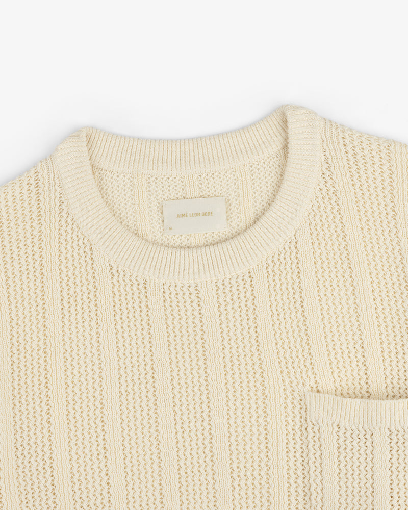 Racking Stitch Crewneck Sweater in beige with ribbed collar and chest pocket, shown flat on a white background.