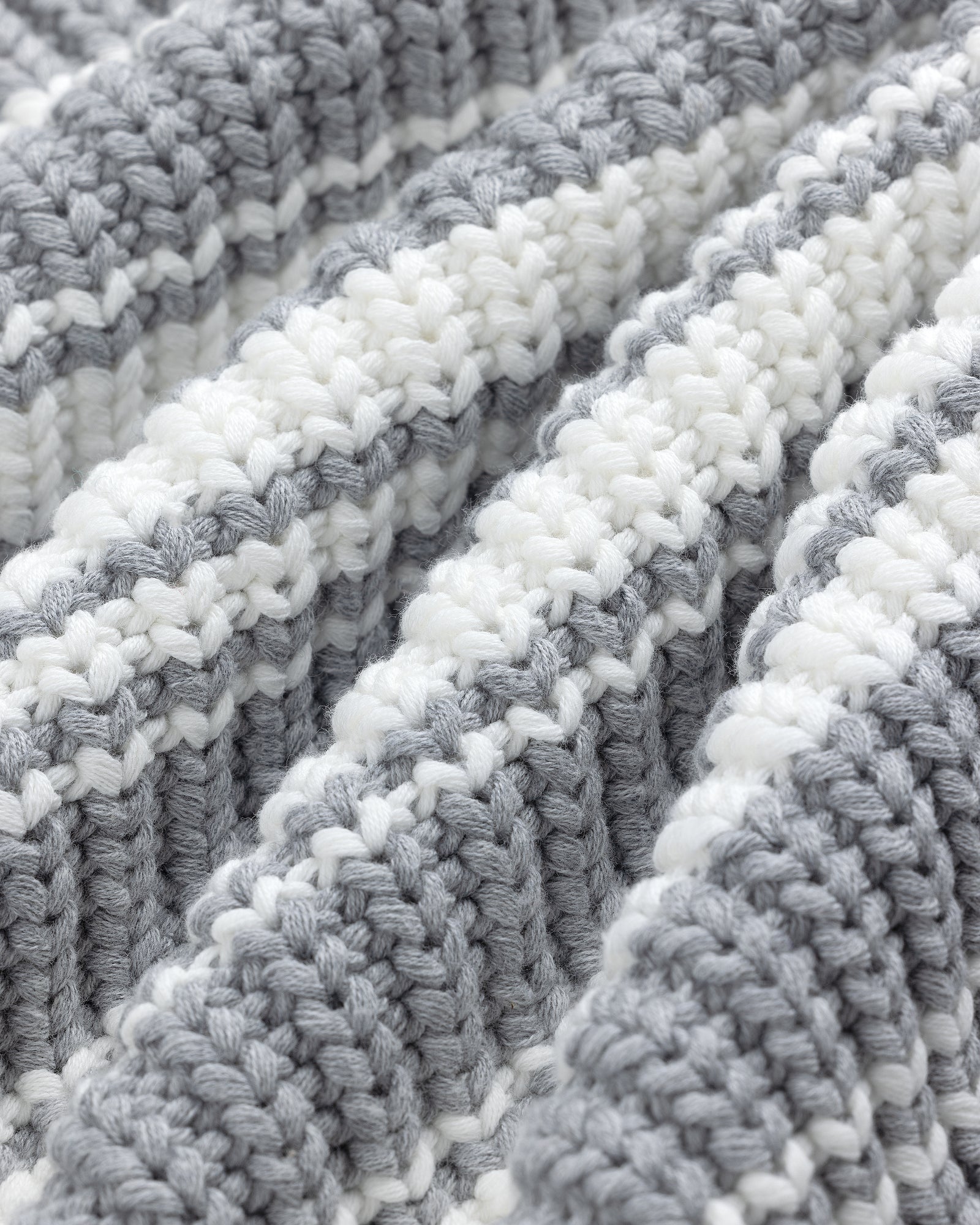Close-up of the Striped Crewneck Sweater's textured fabric with alternating white and gray horizontal stripes.