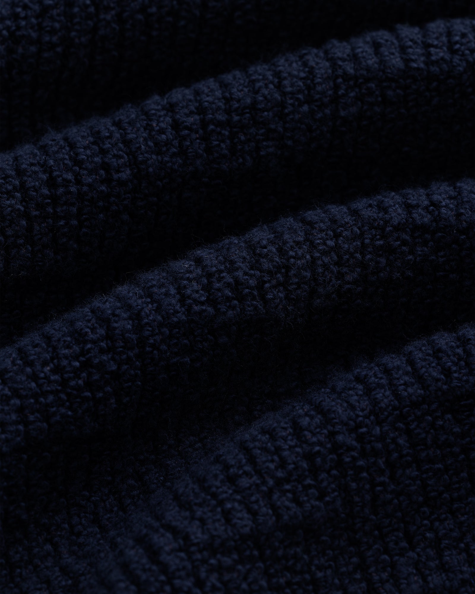 Close-up of the Long-Sleeve Boucle Polo in dark blue, highlighting its soft, ribbed knit texture and raised lines.