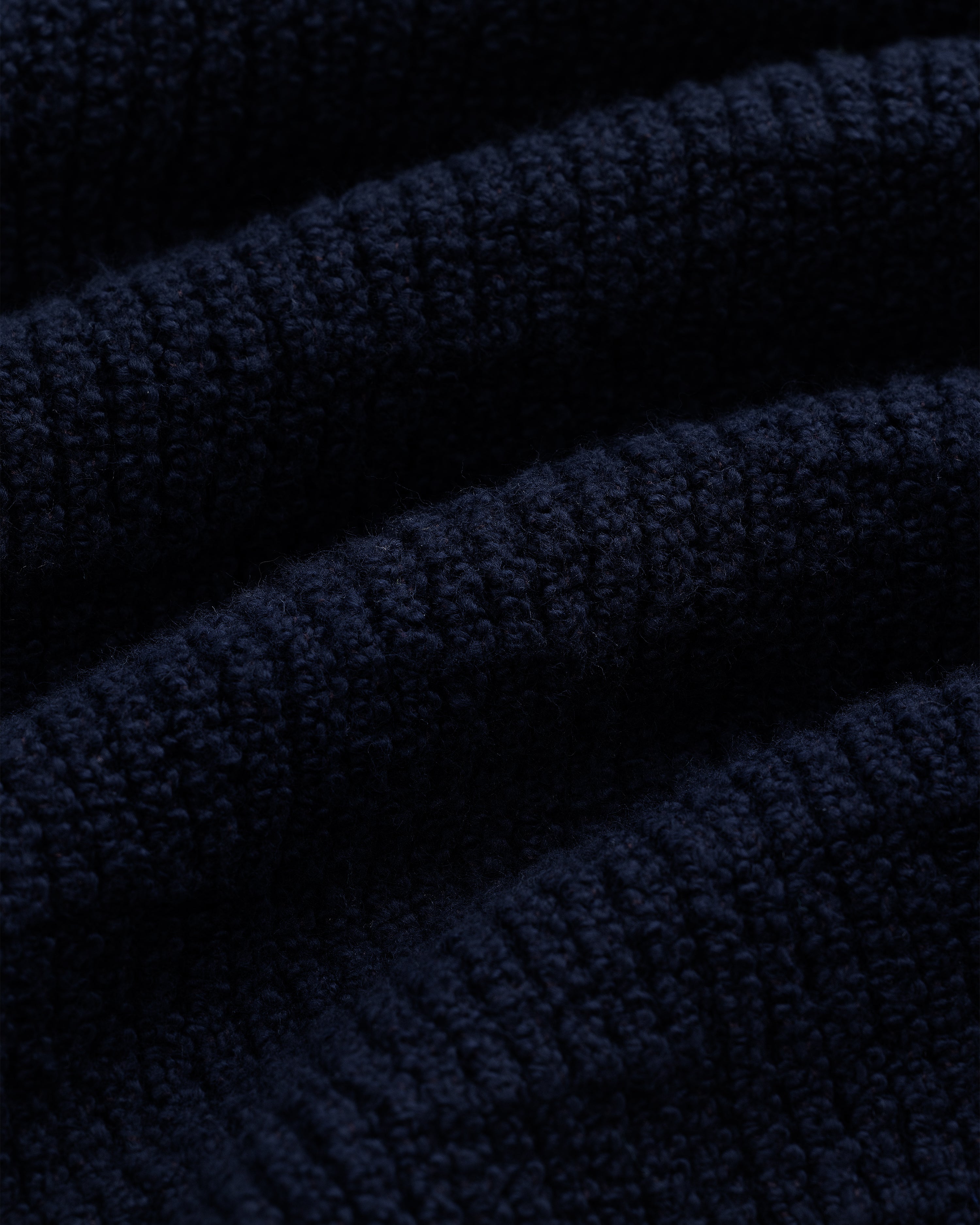 Close-up of the Long-Sleeve Boucle Polo in dark blue, highlighting its soft, ribbed knit texture and raised lines.