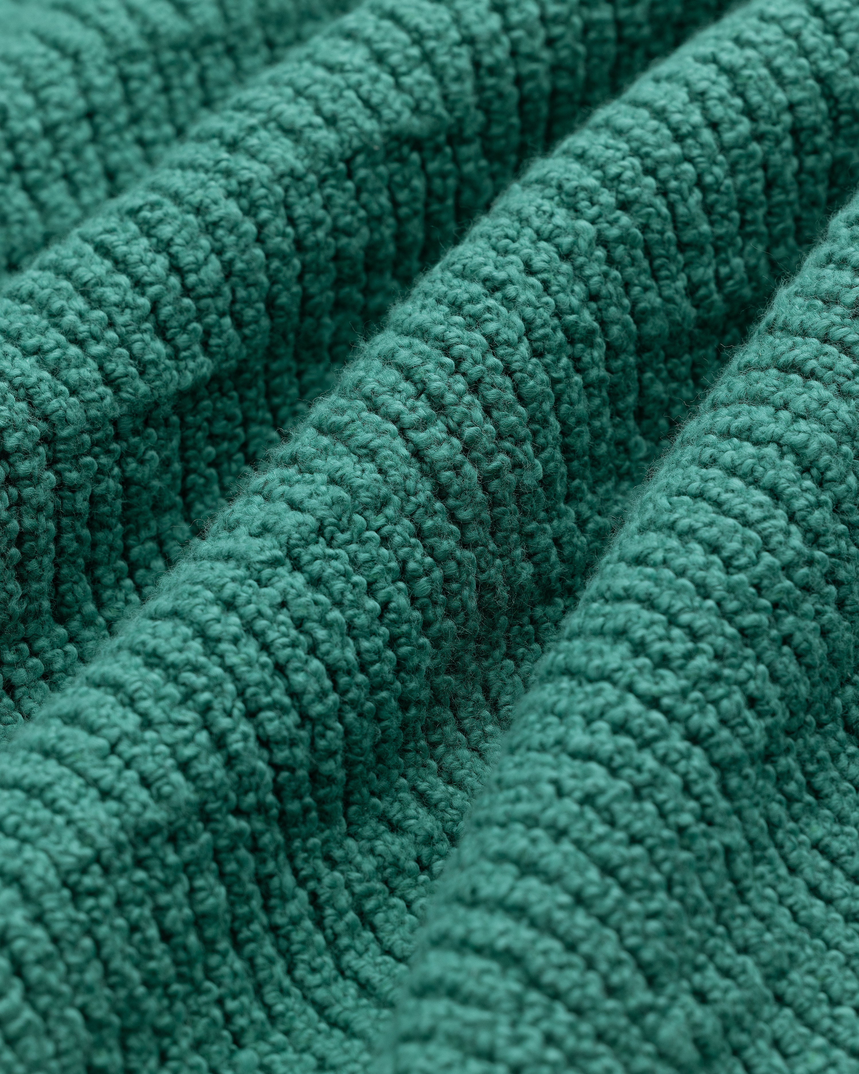 Close-up of the Long-Sleeve Boucle Polo's textured green fabric with raised, ribbed patterns and woven details.