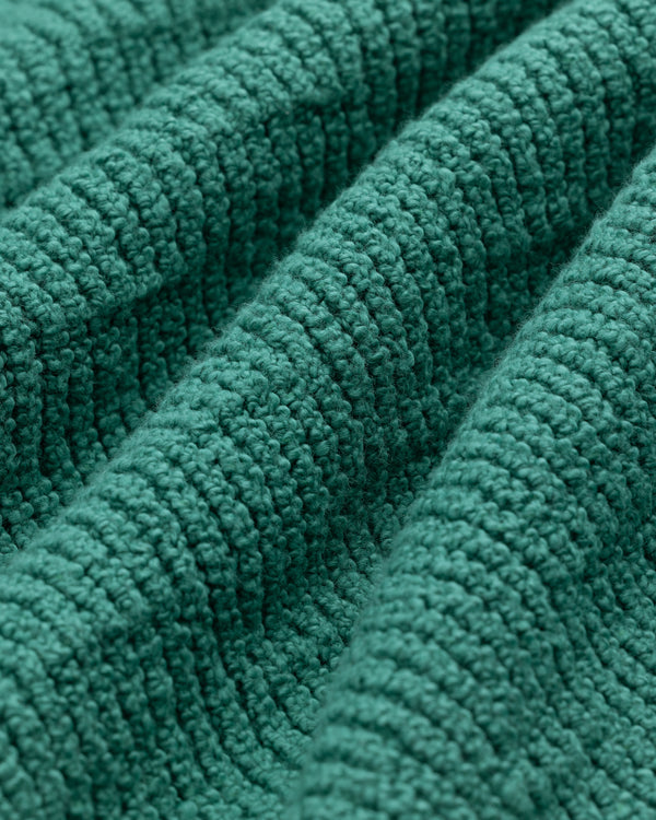 Close-up of the Long-Sleeve Boucle Polo's textured green fabric with raised, ribbed patterns and woven details.
