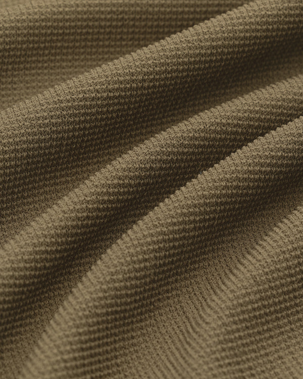 Close-up of the Knit Polo’s brown textured fabric with visible knit pattern and gentle, wavy folds.