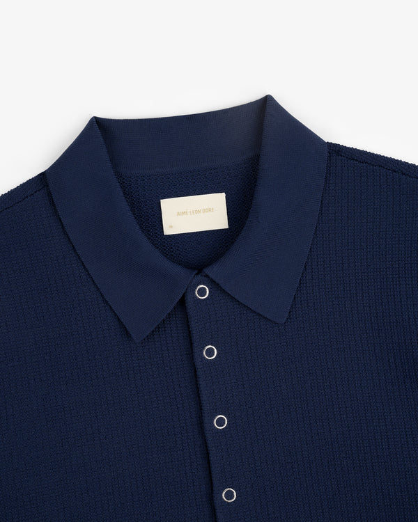 Navy Knit Polo with short sleeves, textured fabric, and metal snap buttons, viewed from above.