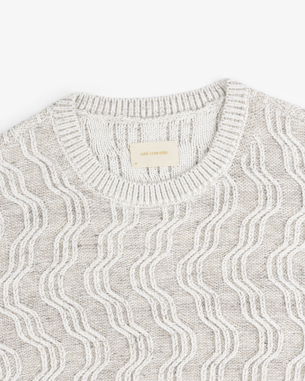 Linen Blend Cable Knit Sweater in beige with a wavy pattern and ribbed crew neckline, laid flat.