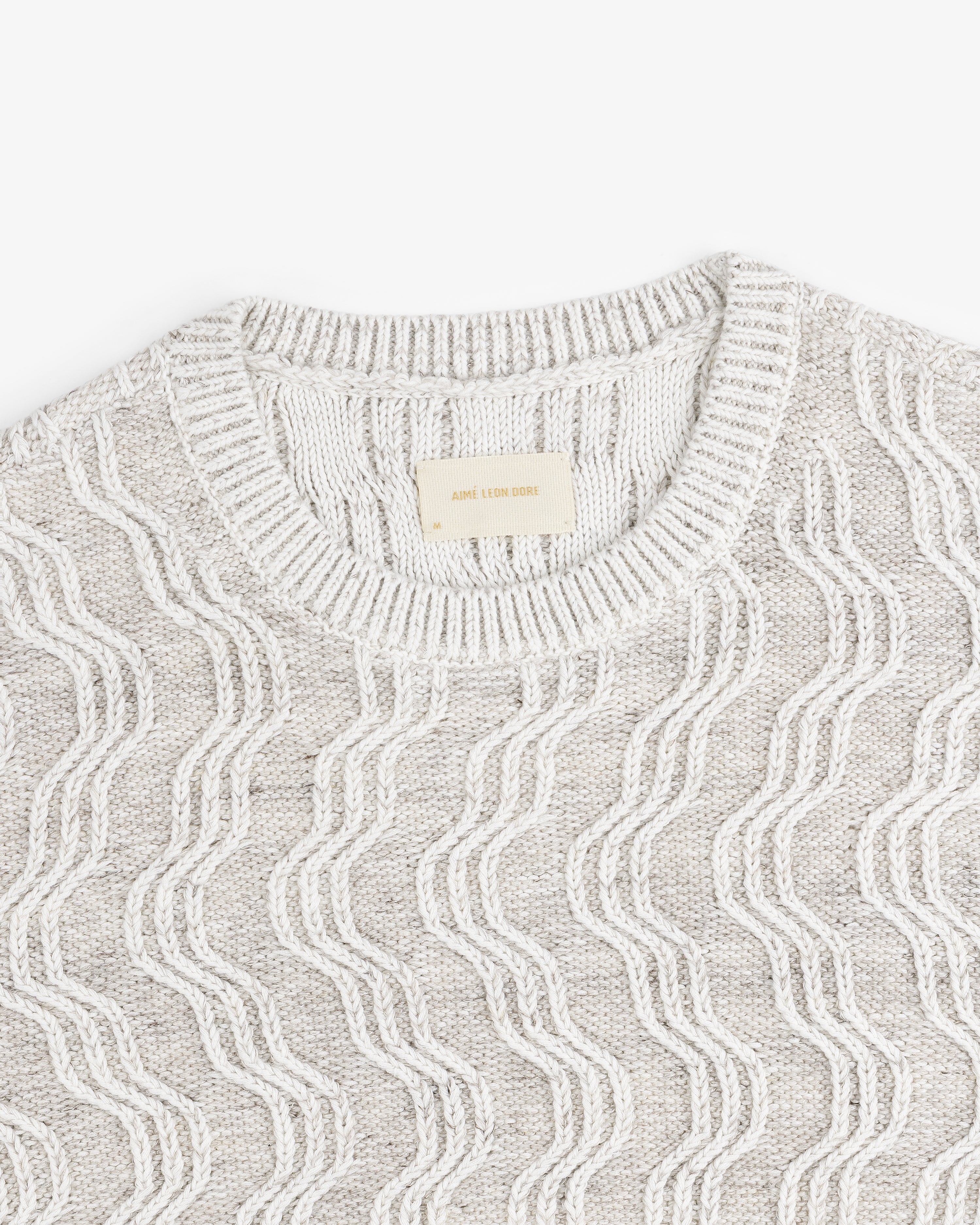 Linen Blend Cable Knit Sweater in beige with a wavy pattern and ribbed crew neckline, laid flat.