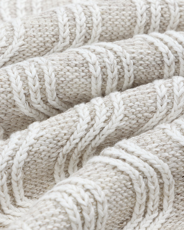 Close-up of a folded Linen Blend Cable Knit Sweater in cream with a cable-knit pattern.