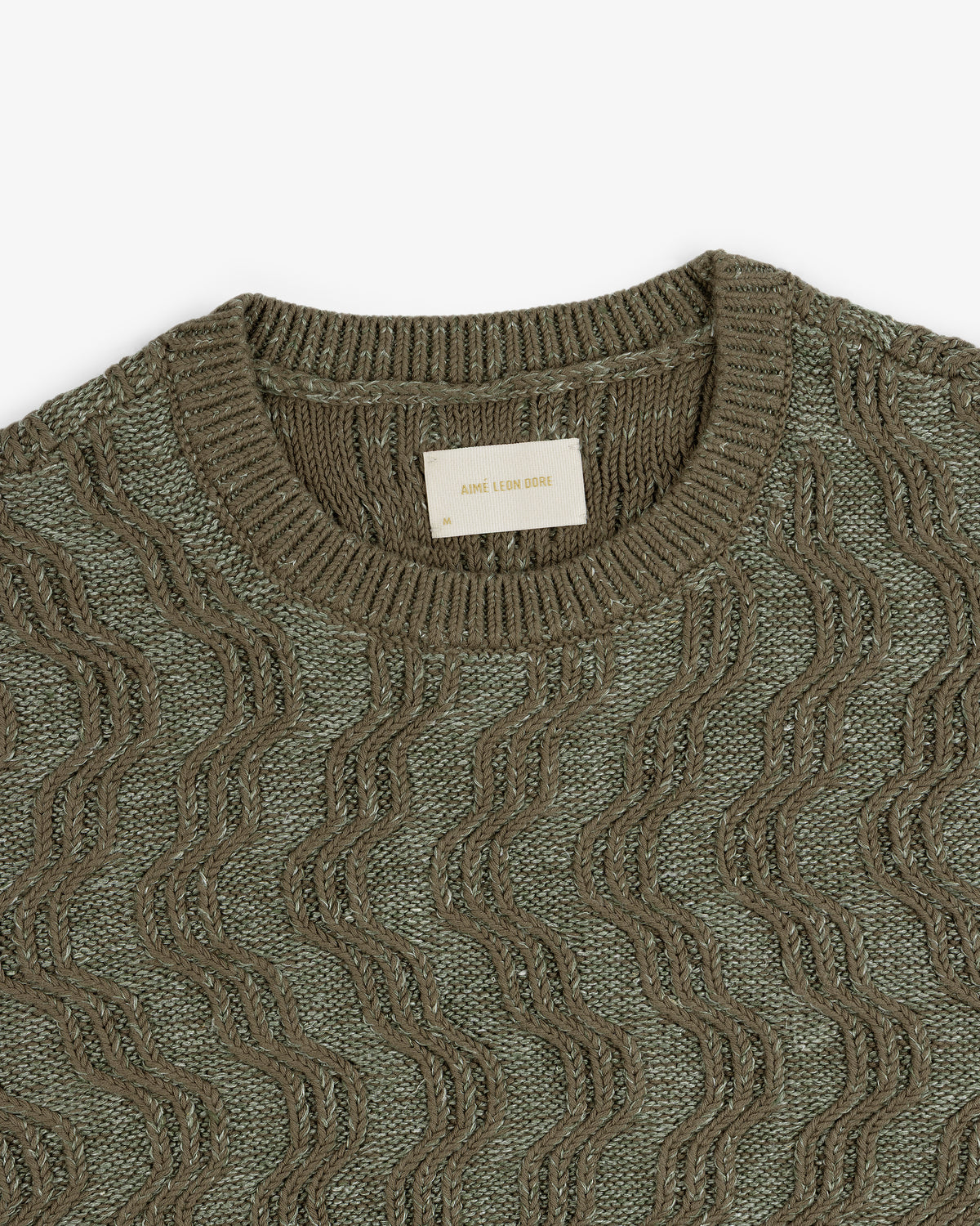 Olive green Linen Blend Cable Knit Sweater with a wavy pattern and Aimé Leon Dore label at the neckline.