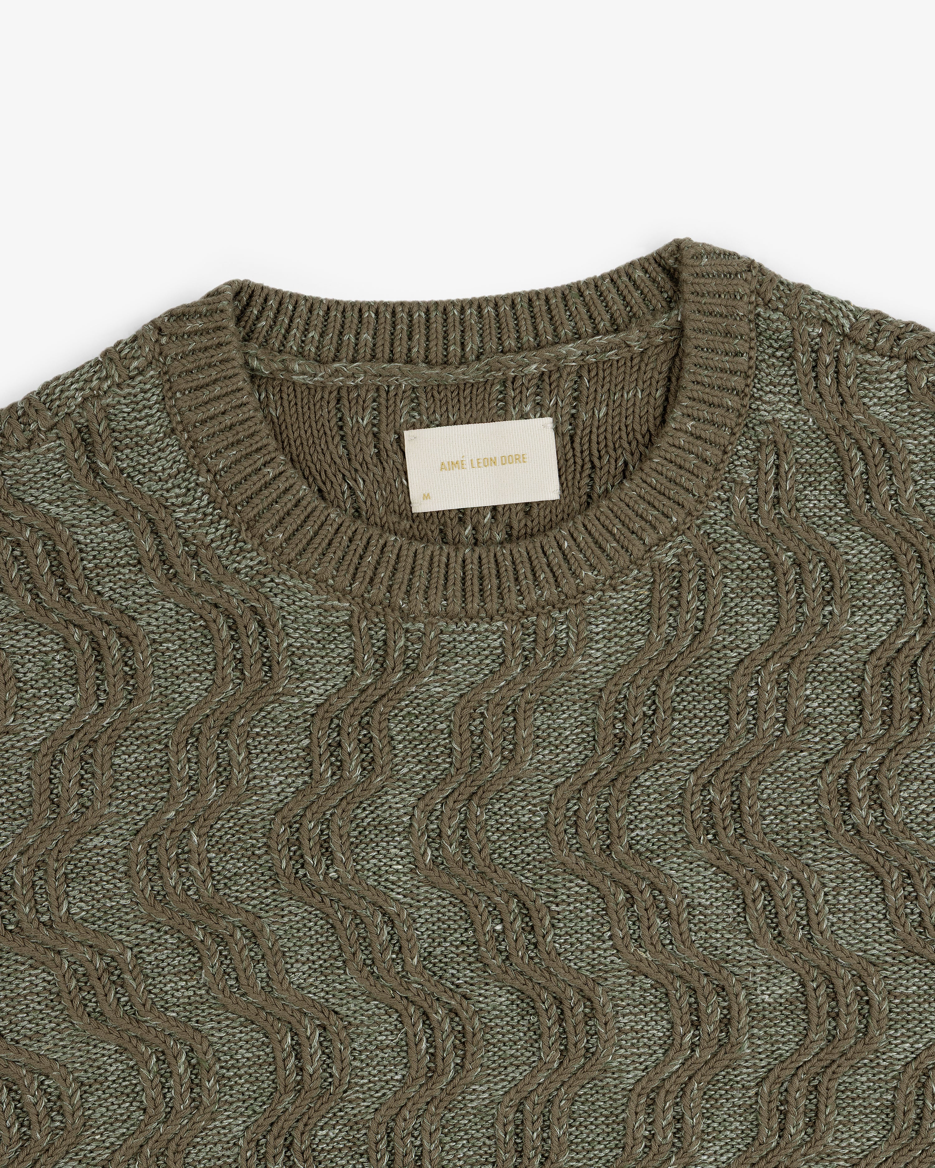 Olive green Linen Blend Cable Knit Sweater with a wavy pattern and Aimé Leon Dore label at the neckline.