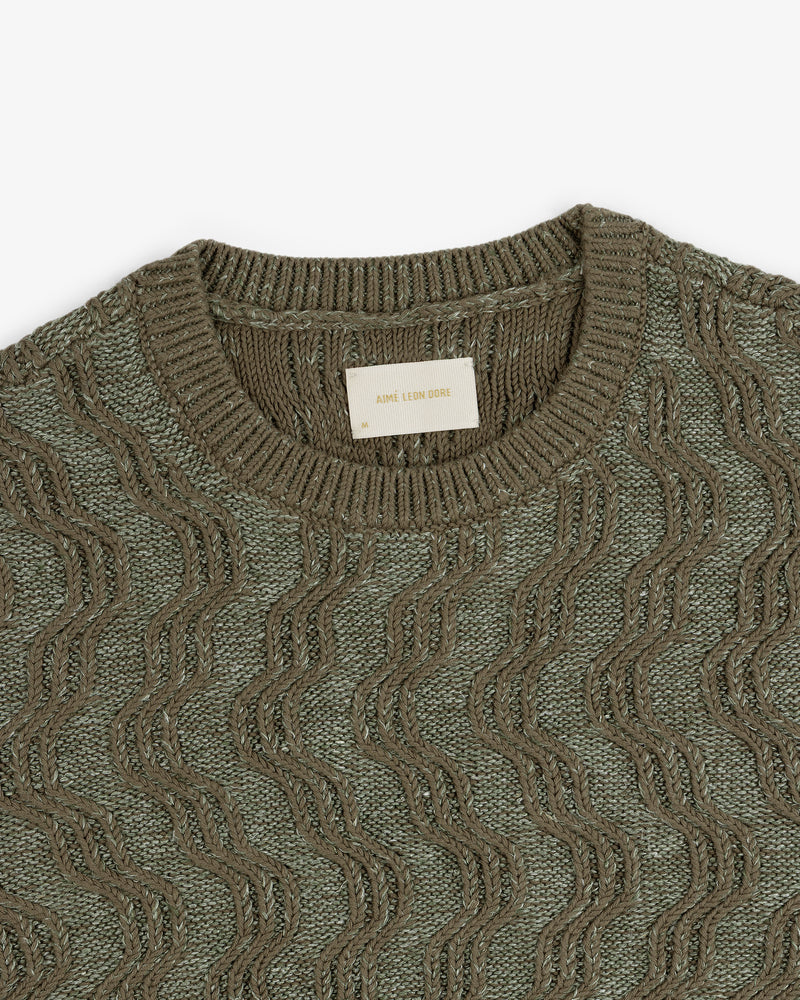 Olive green Linen Blend Cable Knit Sweater with a wavy pattern and Aimé Leon Dore label at the neckline.