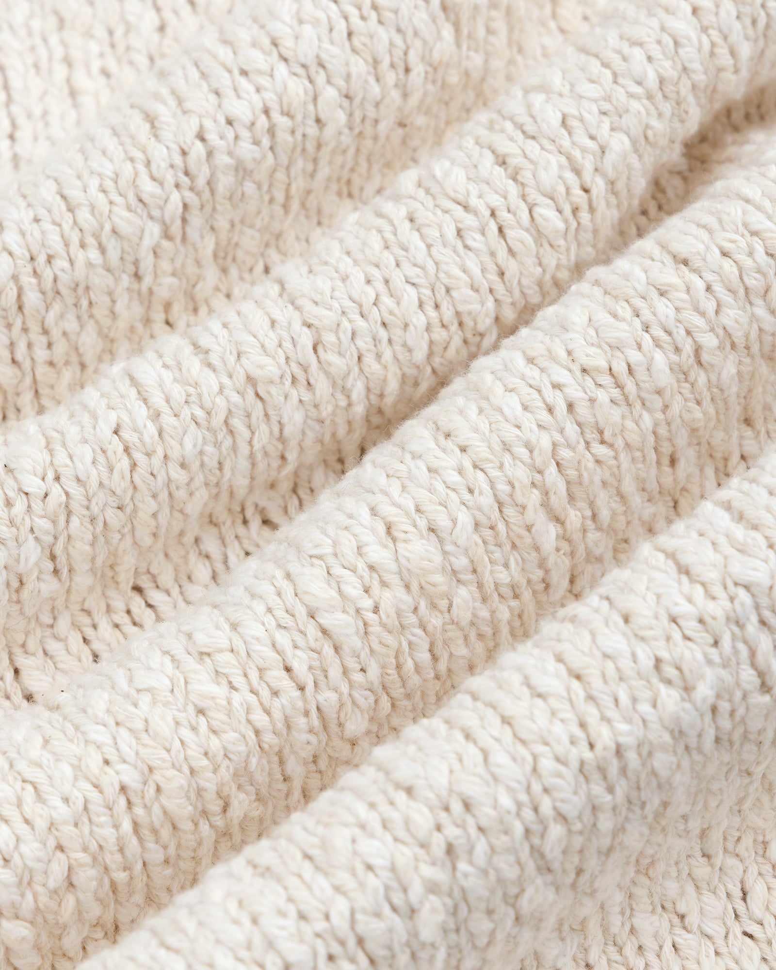 Close-up of the Cotton Slub Cardigan's soft, cream knit fabric with a ribbed, textured pattern.