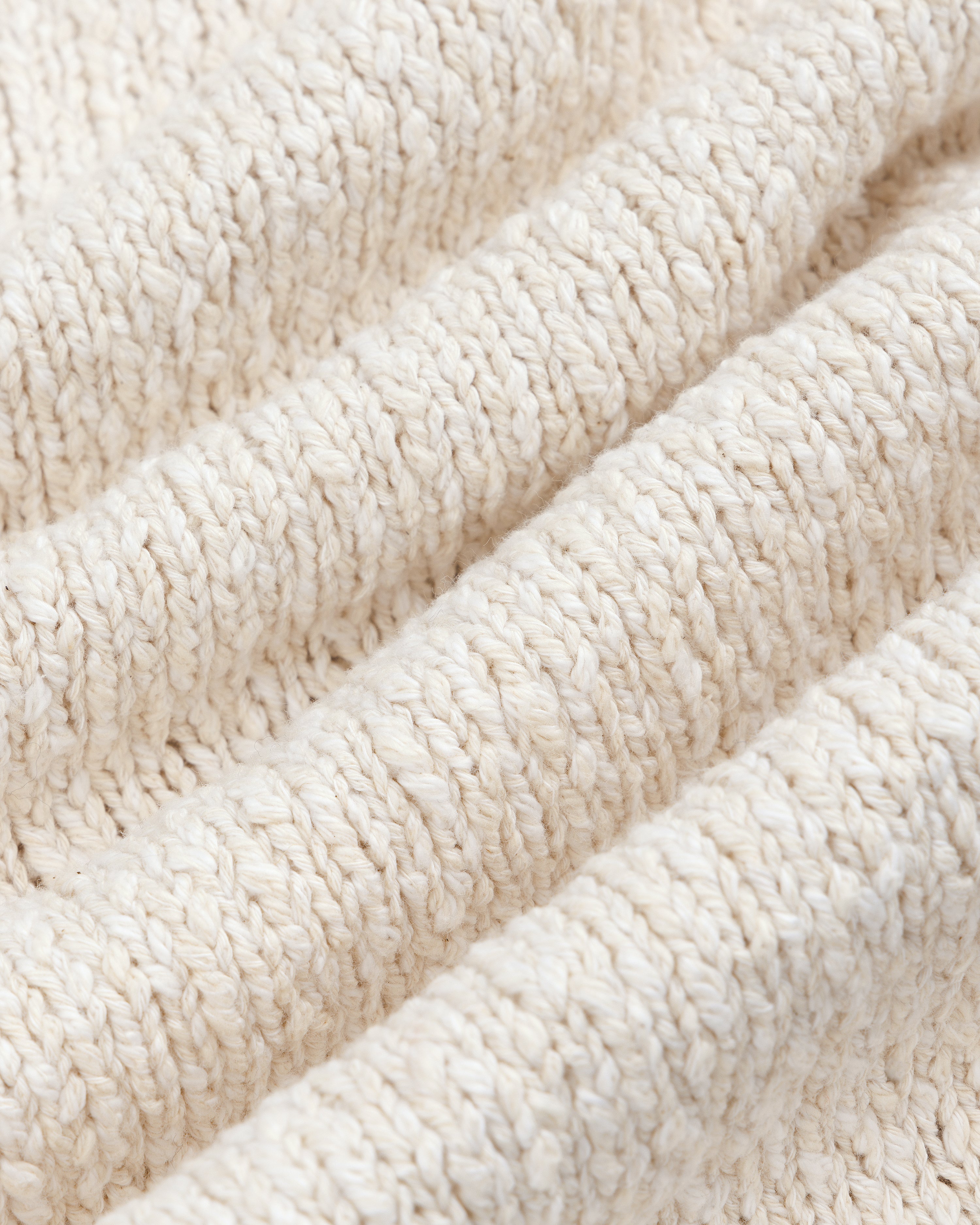 Close-up of the Cotton Slub Cardigan's soft, cream knit fabric with a ribbed, textured pattern.