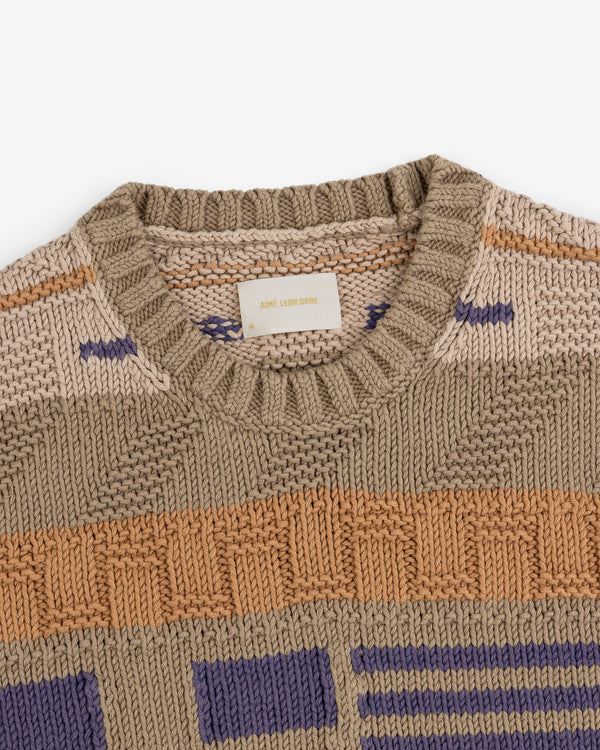 A close-up of the Simaía Crewneck Sweater with geometric patterns in beige, tan, orange, and purple.