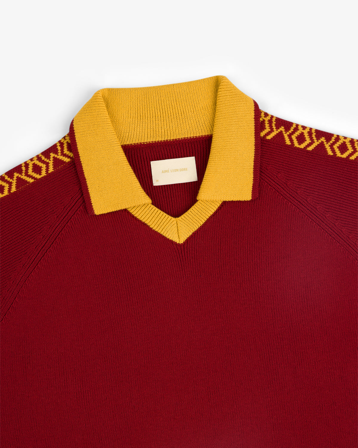 Knit Sport Pullover in maroon with a gold collar and gold patterned shoulder detailing.
