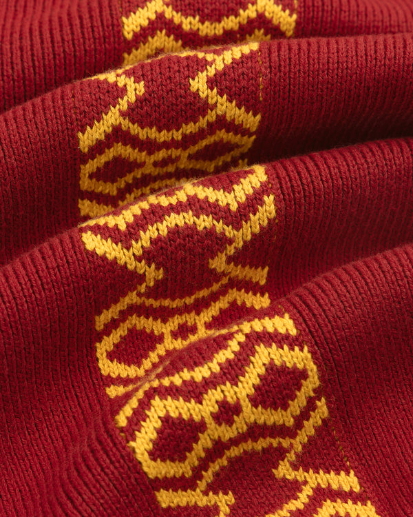 Knit Sport Pullover in red knit with a yellow geometric center pattern, shown folded in a close-up view.