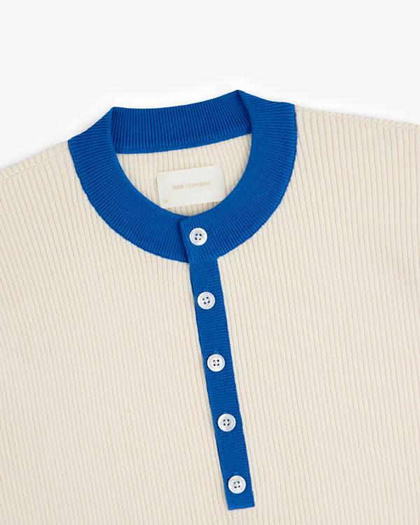 Sport Knit Henley in beige ribbed fabric with blue collar, placket, and white buttons, shown on a white background.