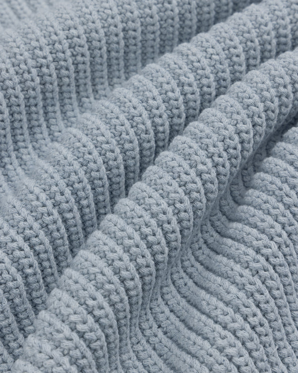 Close-up of the Knit Denim Crewneck Sweater's light blue, ribbed knit fabric with gentle textured folds.