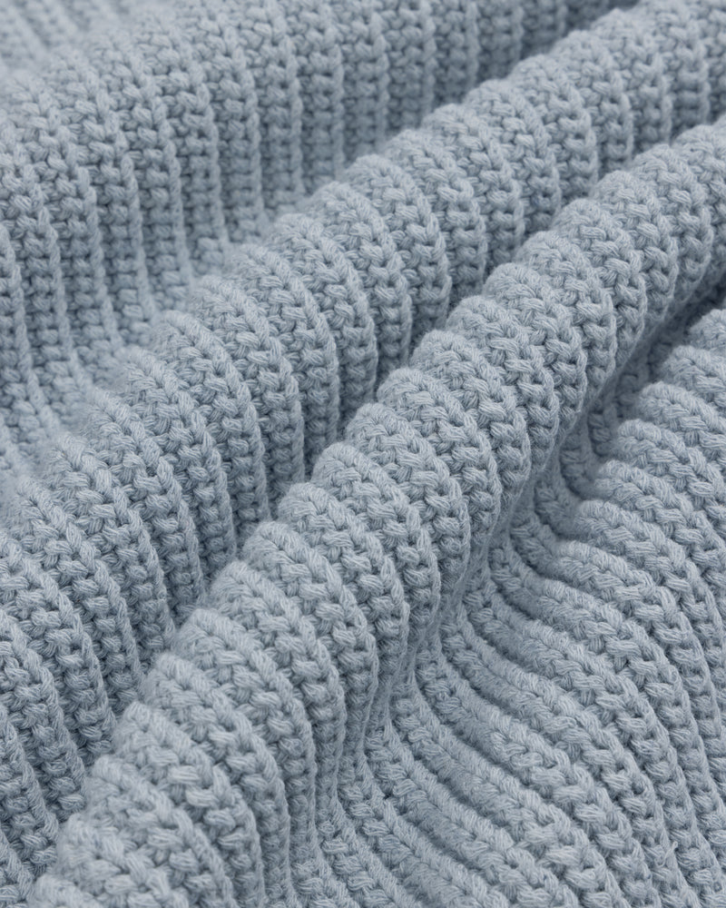 Close-up of the Knit Denim Crewneck Sweater's light blue, ribbed knit fabric with gentle textured folds.