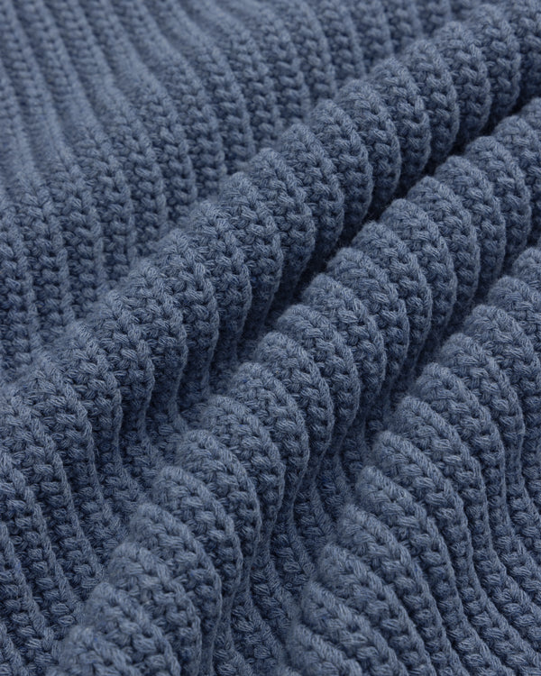 Close-up of the Knit Denim Crewneck Sweater, featuring blue ribbed knit fabric with raised, wavy patterns.
