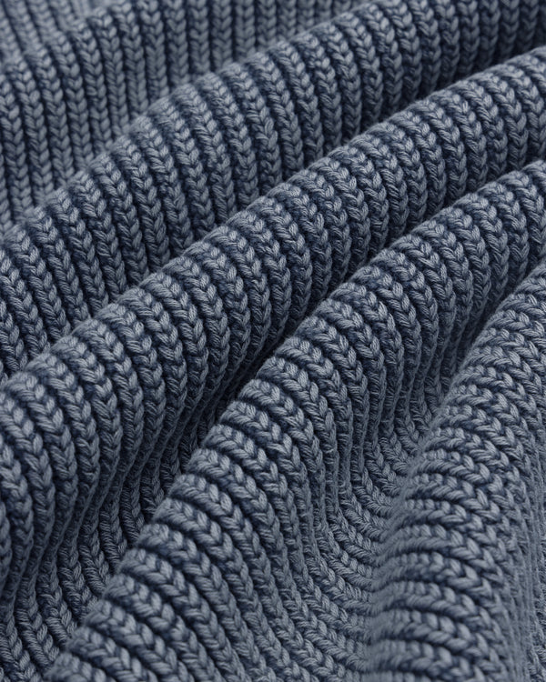 Close-up of the Stone Washed Knit Polo in blue, showing ribbed texture, wavy folds, and detailed stitching.