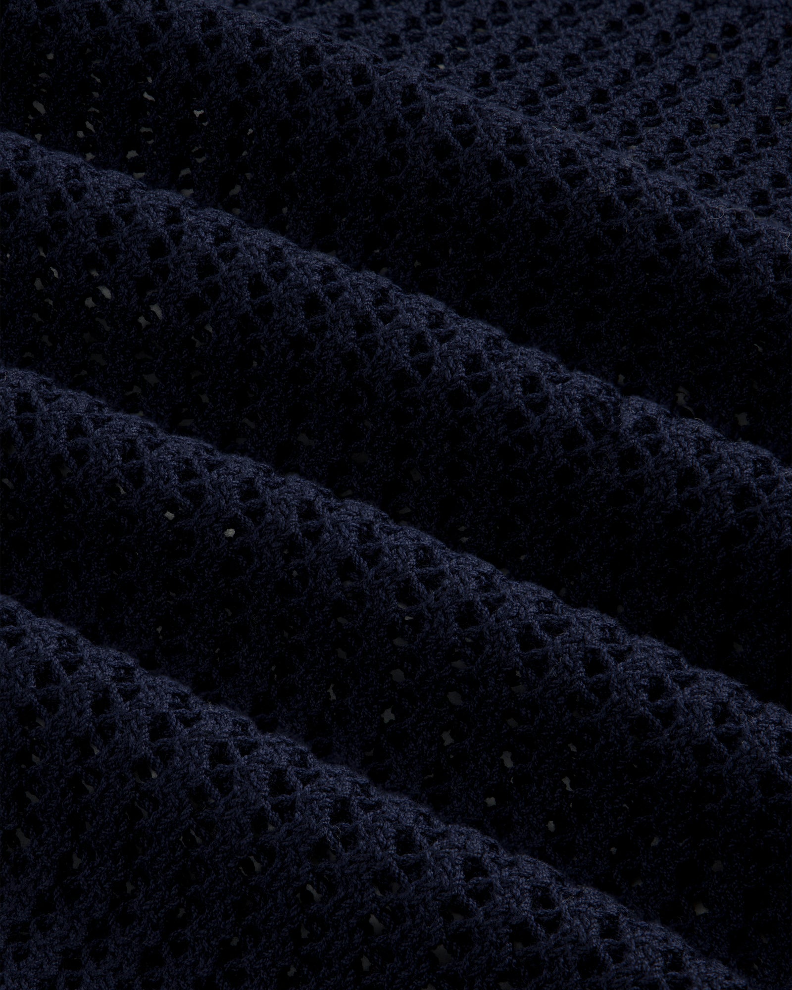 Close-up of Cotton Eyelet Crewneck Sweater in dark blue, featuring small holes and raised textured ridges.