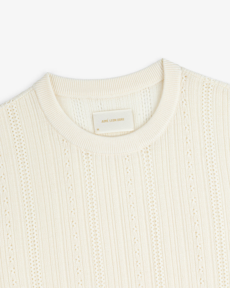 Close-up of the Merino Wool Eyelet Tee in cream, featuring textured knit, ribbed crew neck, and vertical patterns.