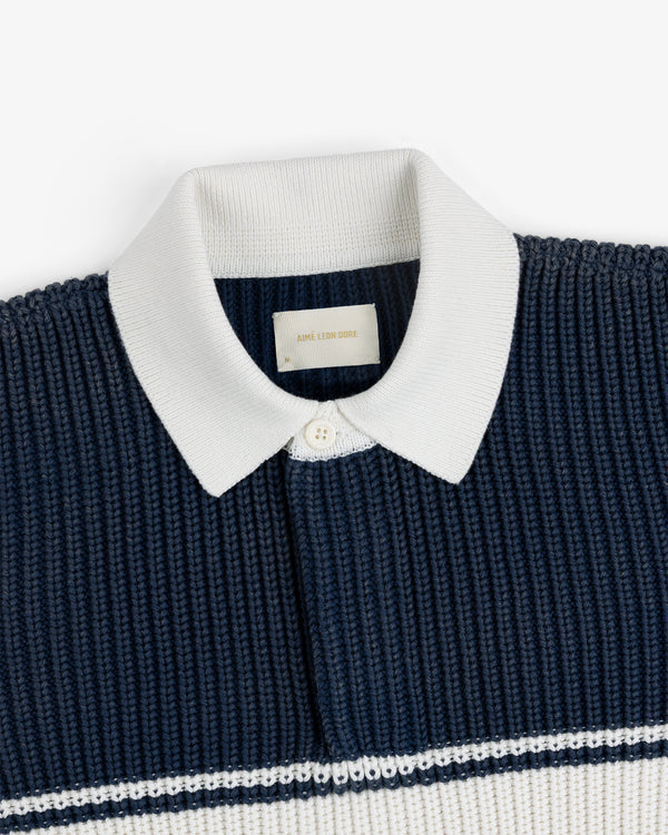 Striped Knit Rugby in navy with a white ribbed collar and white horizontal stripe, shown flat on a white background.