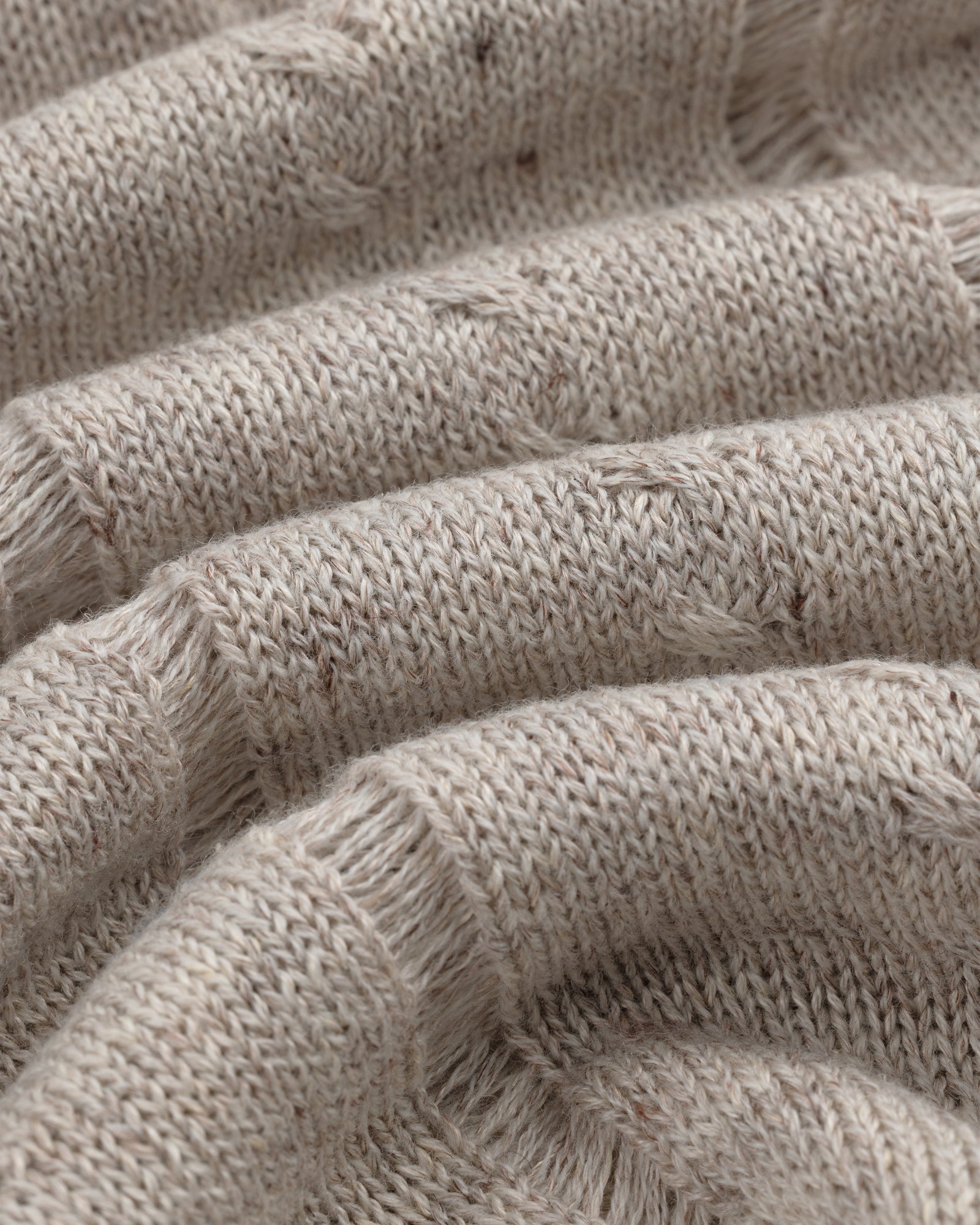 Close-up of a Pointelle Tank Top in beige knit with ribbed texture, visible stitches, and soft wavy folds.
