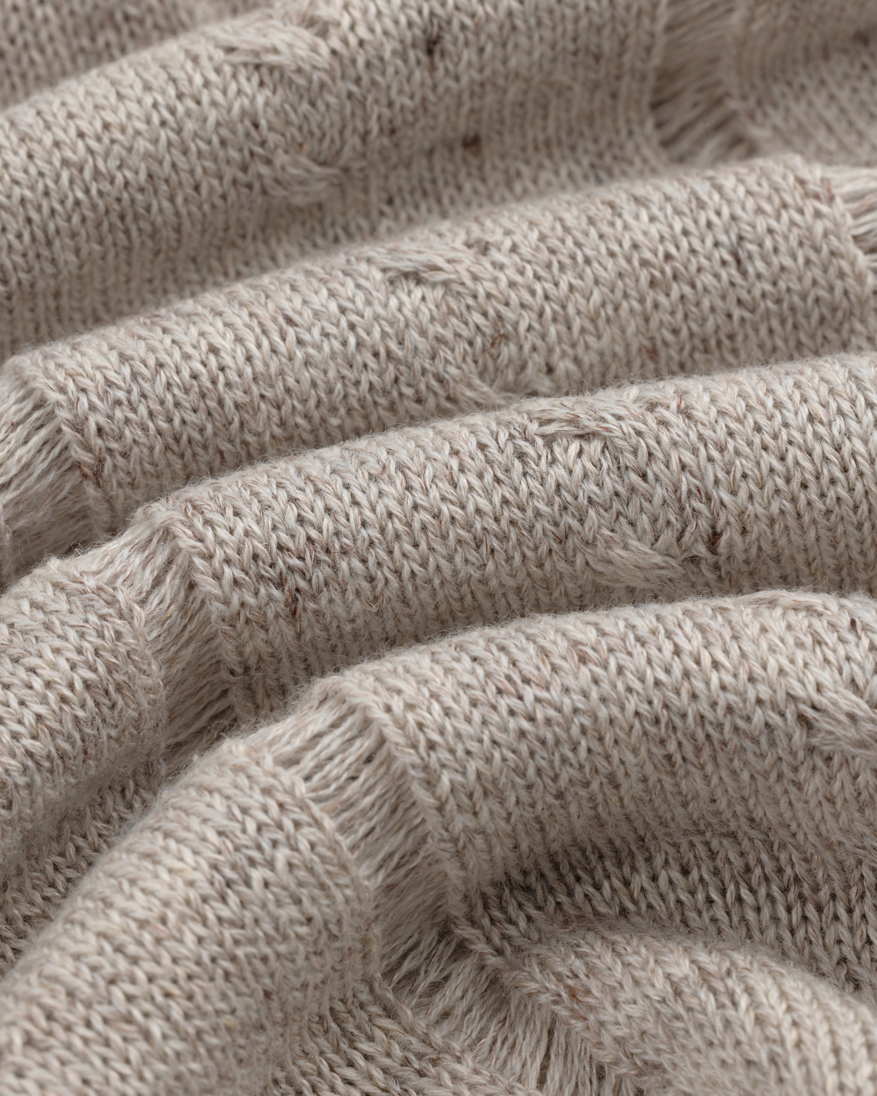 Close-up of a Pointelle Tank Top in beige knit with ribbed texture, visible stitches, and soft wavy folds.