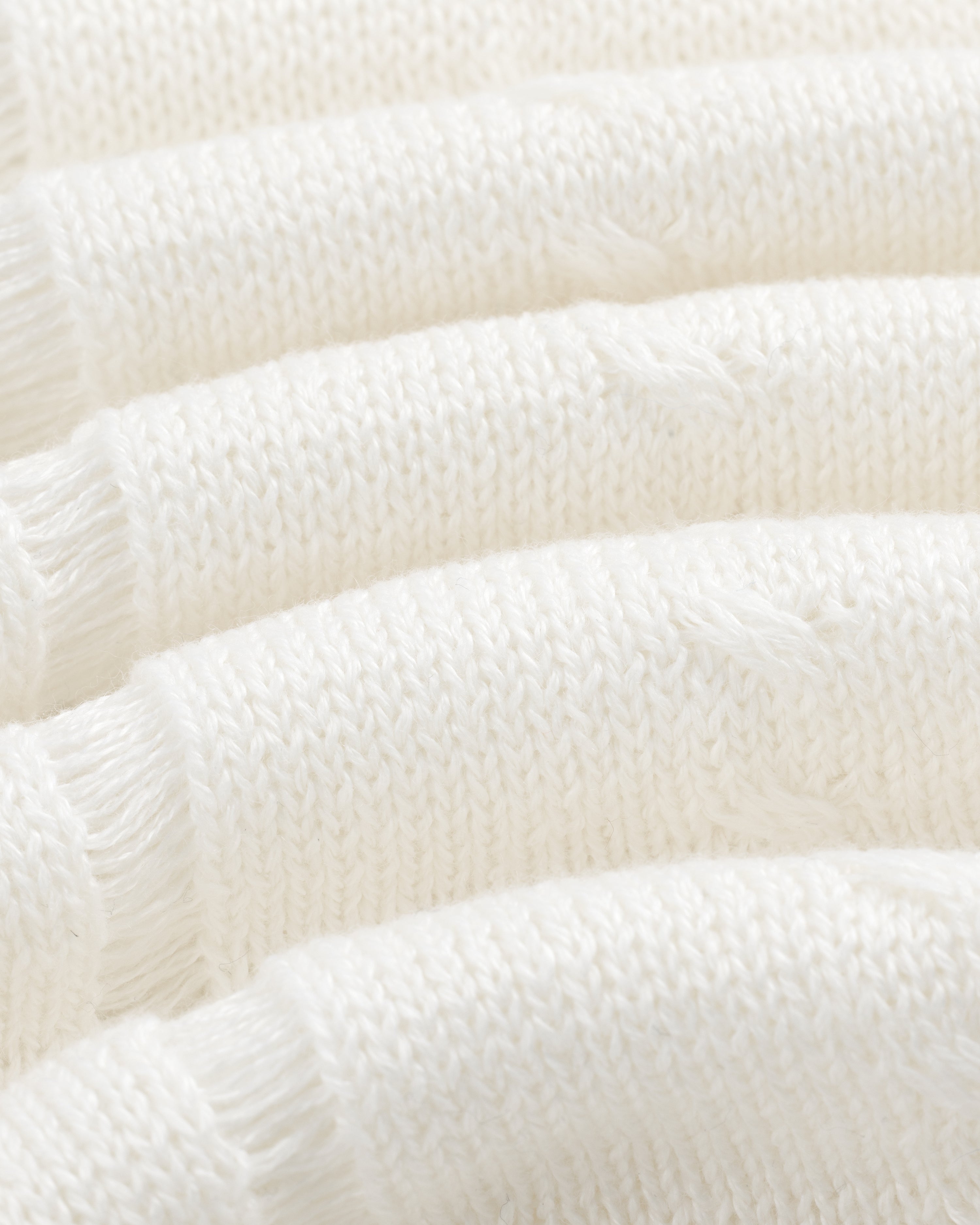 Close-up of Pointelle Tank Top's soft white knit fabric with horizontal textured ridges and loose threads.