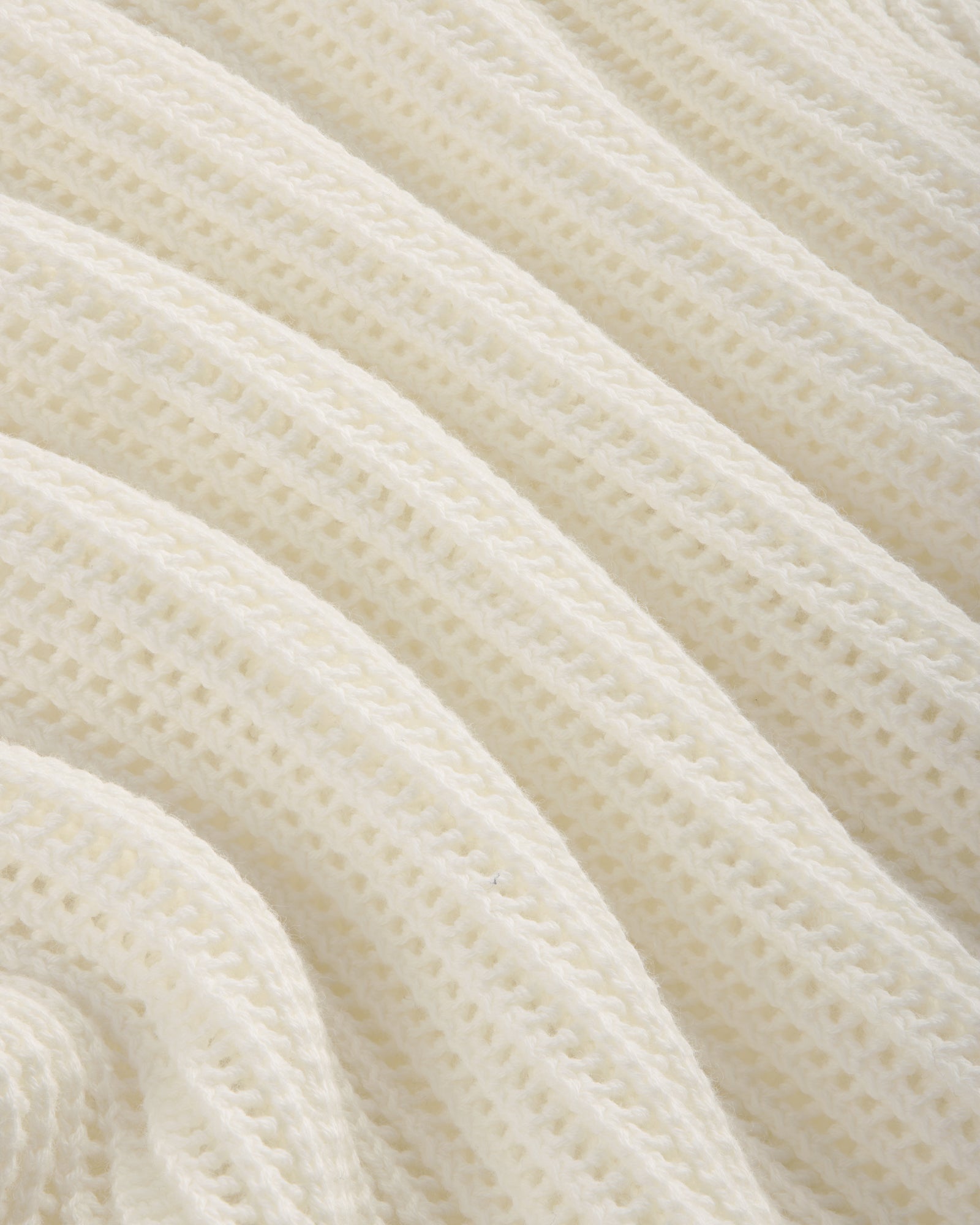 Close-up of the Mesh Knit Polo's soft, white ribbed fabric with a wavy, textured pattern.
