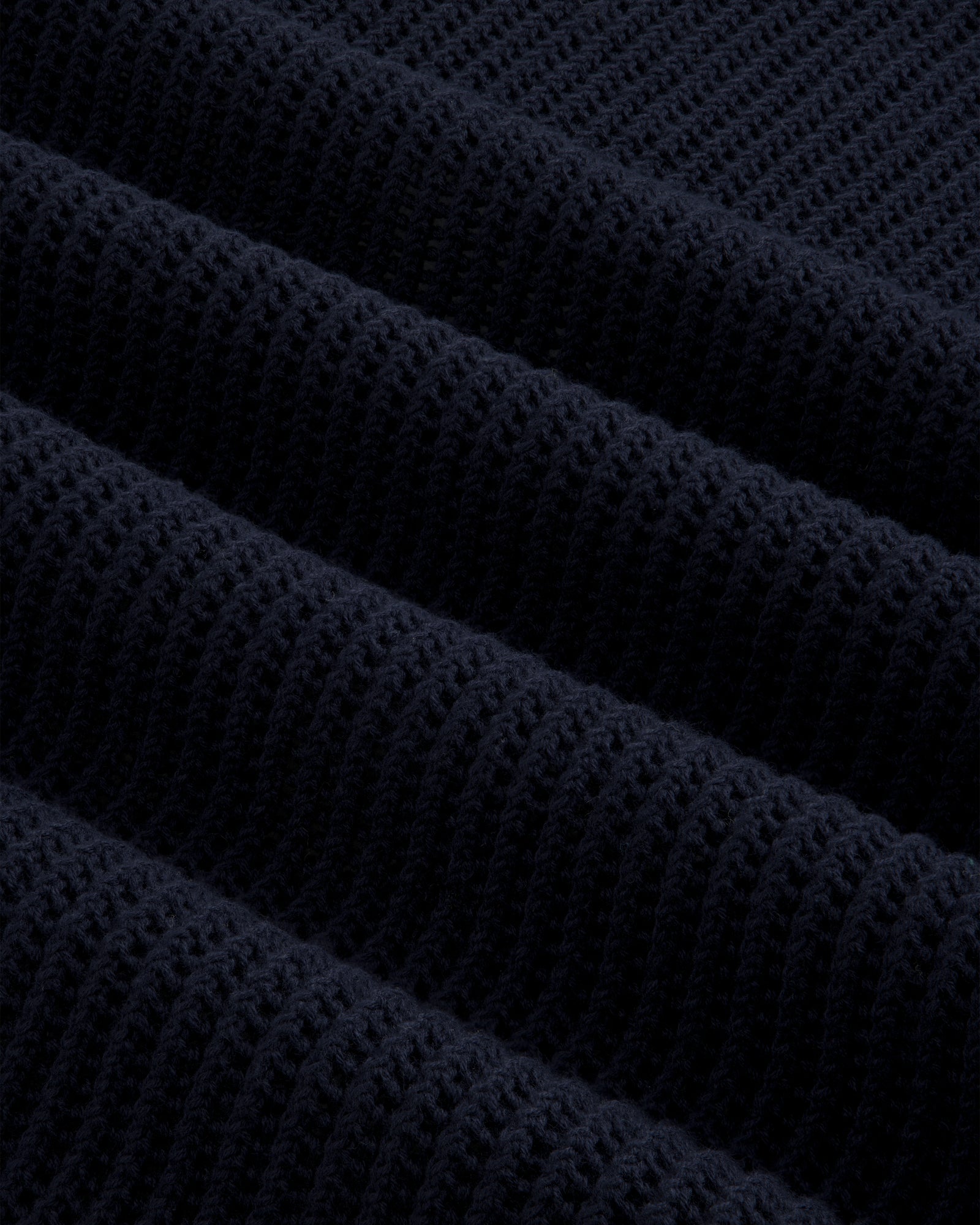Close-up of dark blue Mesh Knit Polo, highlighting ribbed texture with horizontal ridges and soft material detail.
