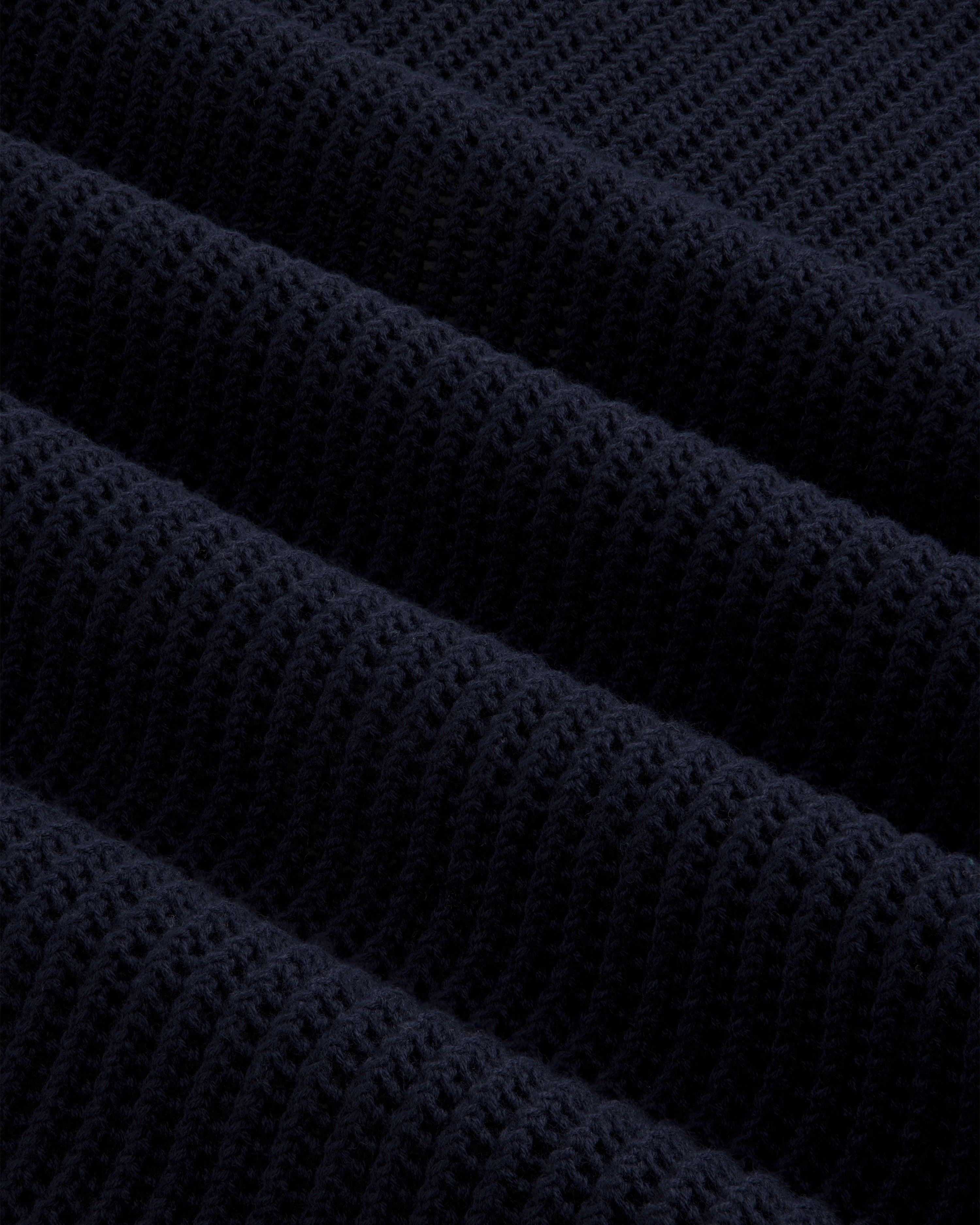 Close-up of dark blue Mesh Knit Polo, highlighting ribbed texture with horizontal ridges and soft material detail.