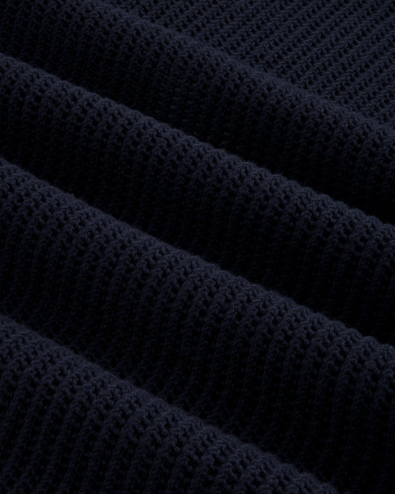 Close-up of dark blue Mesh Knit Polo, highlighting ribbed texture with horizontal ridges and soft material detail.