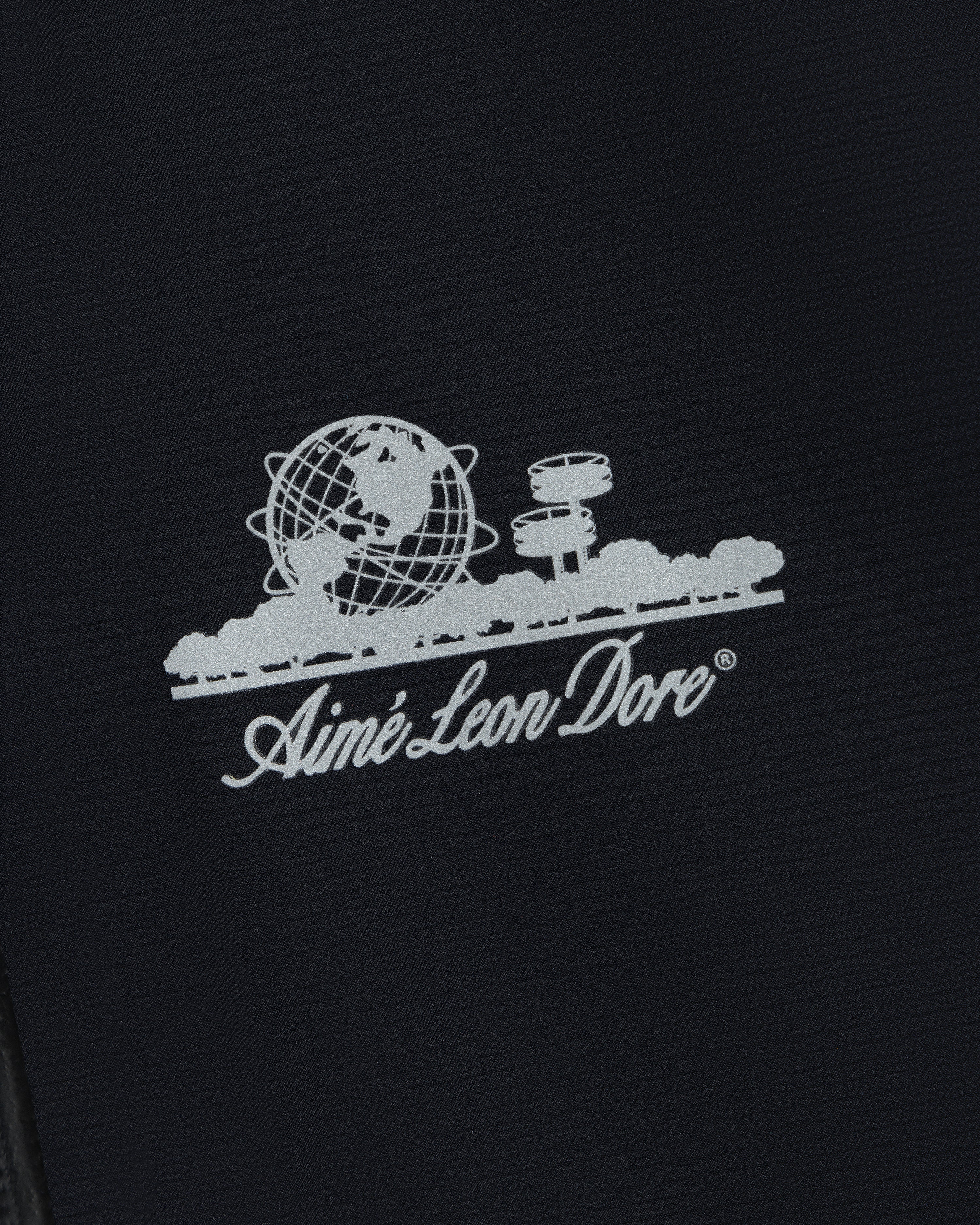 White Aimé Leon Dore logo with globe, trees, and buildings on the Lightweight GORE-TEX Shell Jacket.