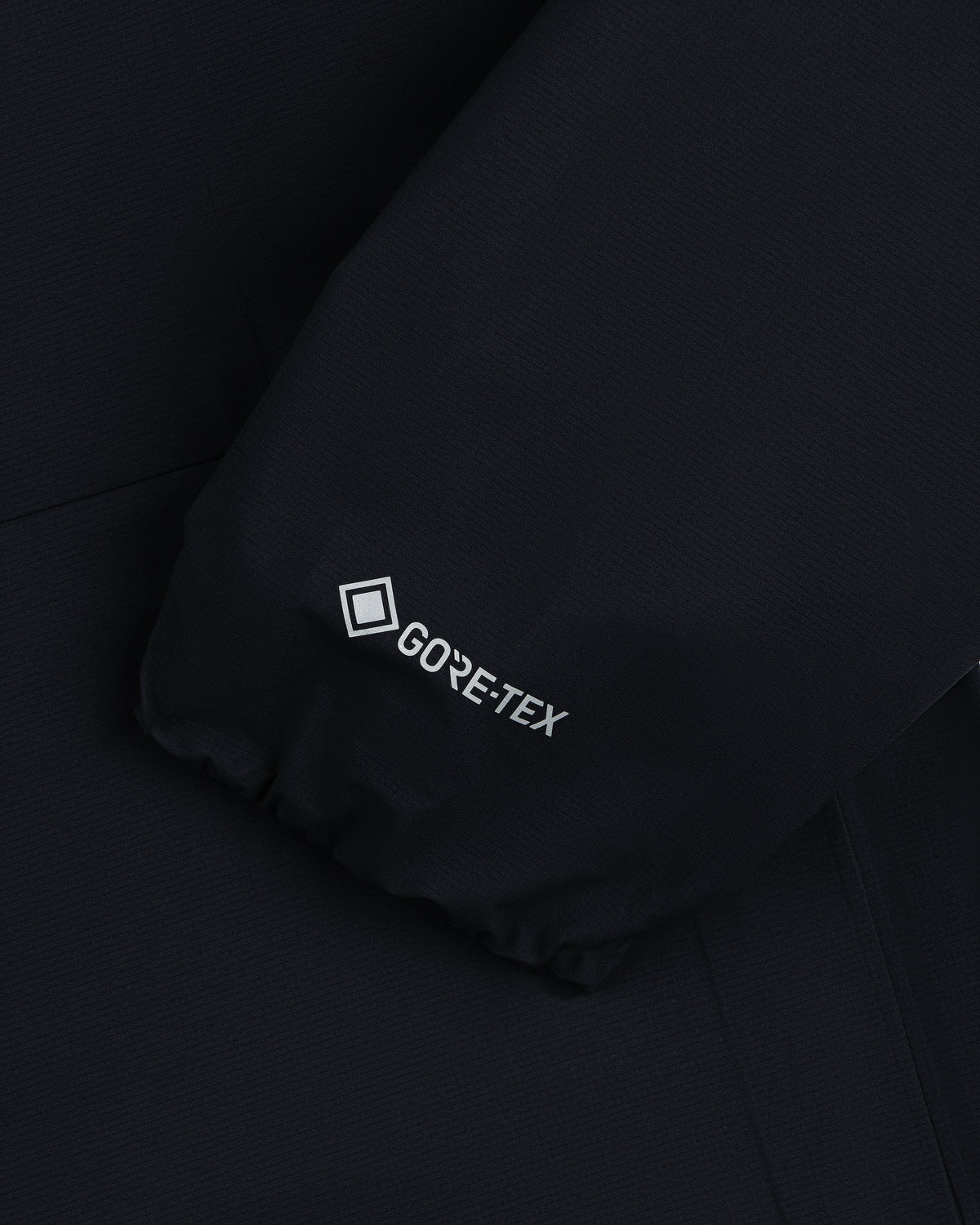 Close-up of a Lightweight GORE-TEX Shell Jacket's black sleeve with the white GORE-TEX logo near the cuff.