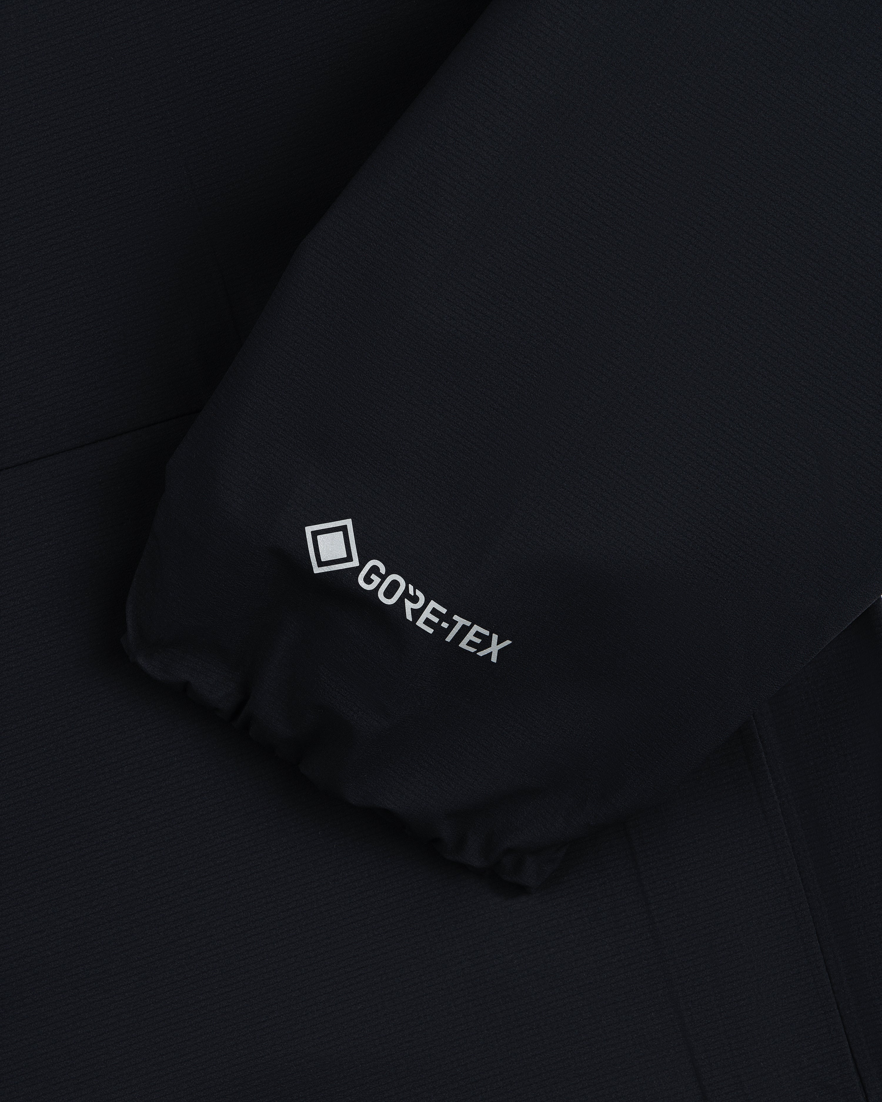 Close-up of a Lightweight GORE-TEX Shell Jacket's black sleeve with the white GORE-TEX logo near the cuff.
