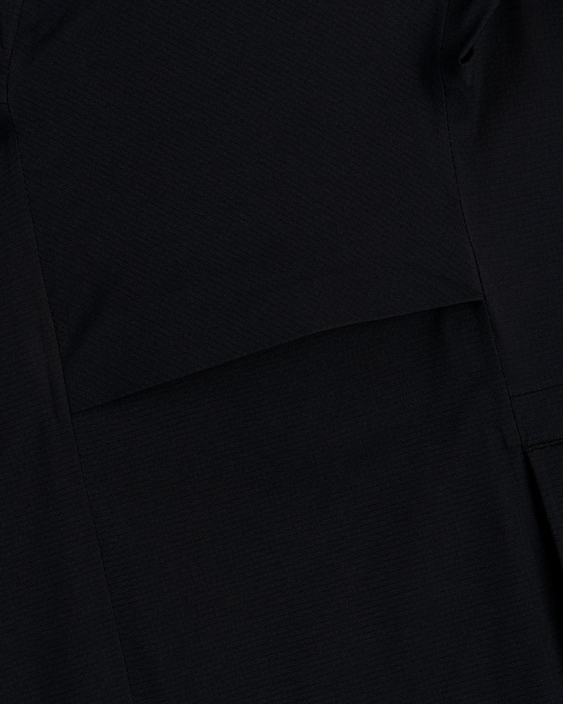 Close-up of a Lightweight GORE-TEX Shell Jacket in black, showing visible stitching and overlapping fabric layers.