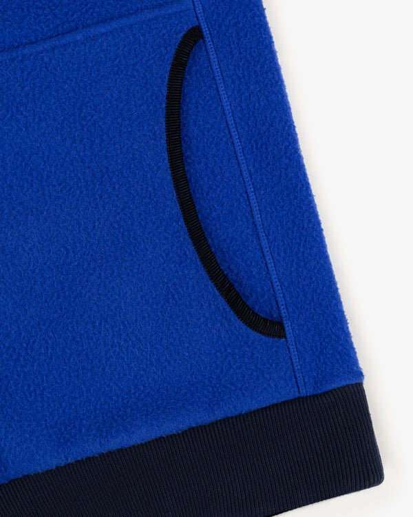 Close-up of Casentino Crest Half-Zip Pullover in blue with black-trimmed pocket and ribbed hem on white background.