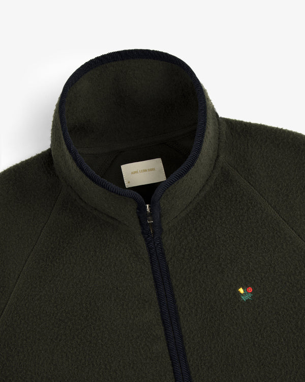 Close-up of the Casentino Crest Half-Zip Pullover, dark green with a zipper and embroidered flower logo on the chest.