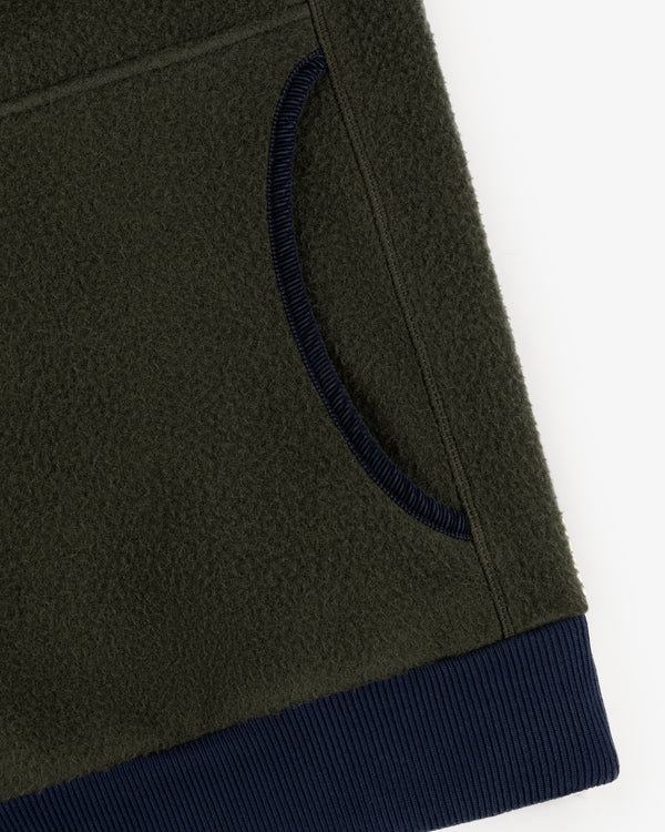 Close-up of the Casentino Crest Half-Zip Pullover in olive green with a navy ribbed pocket trim and waistband.