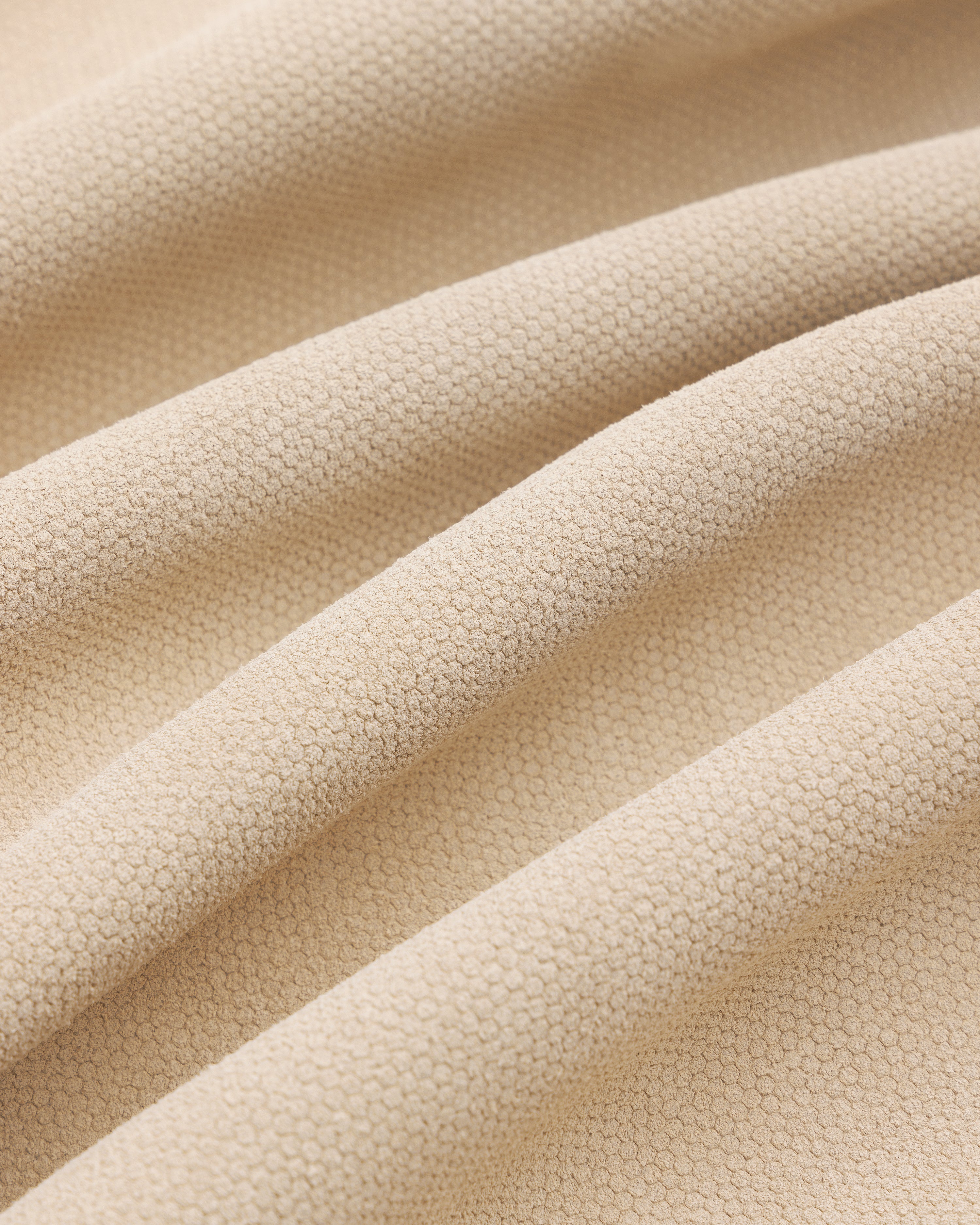 Close-up of the Leather Ranch Jacket's beige textured fabric with small hexagonal patterns and gentle folds.
