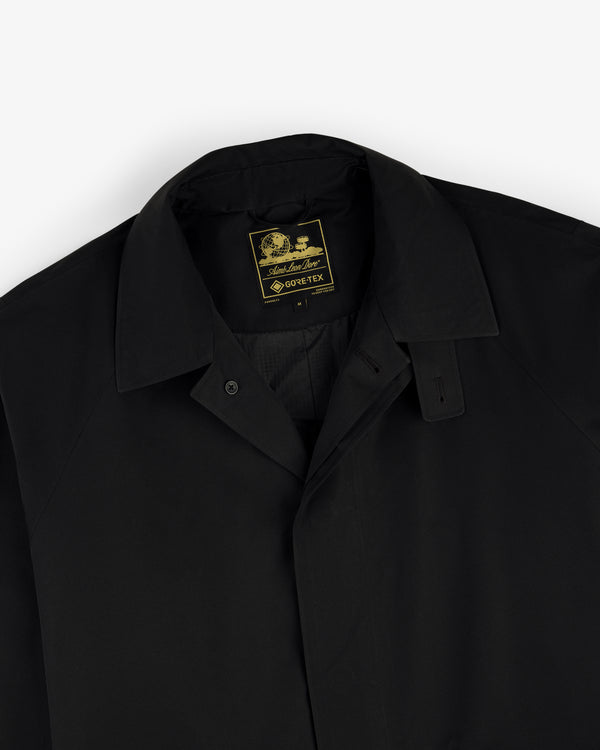 Black GORE-TEX Balmacaan Coat with collar and visible yellow-and-black Gore-Tex label inside the neckline.