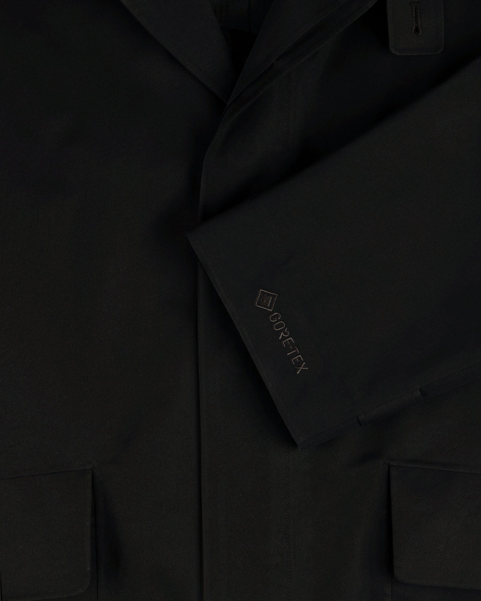 Close-up of the GORE-TEX Balmacaan Coat sleeve with embroidered logo and lower pockets visible.