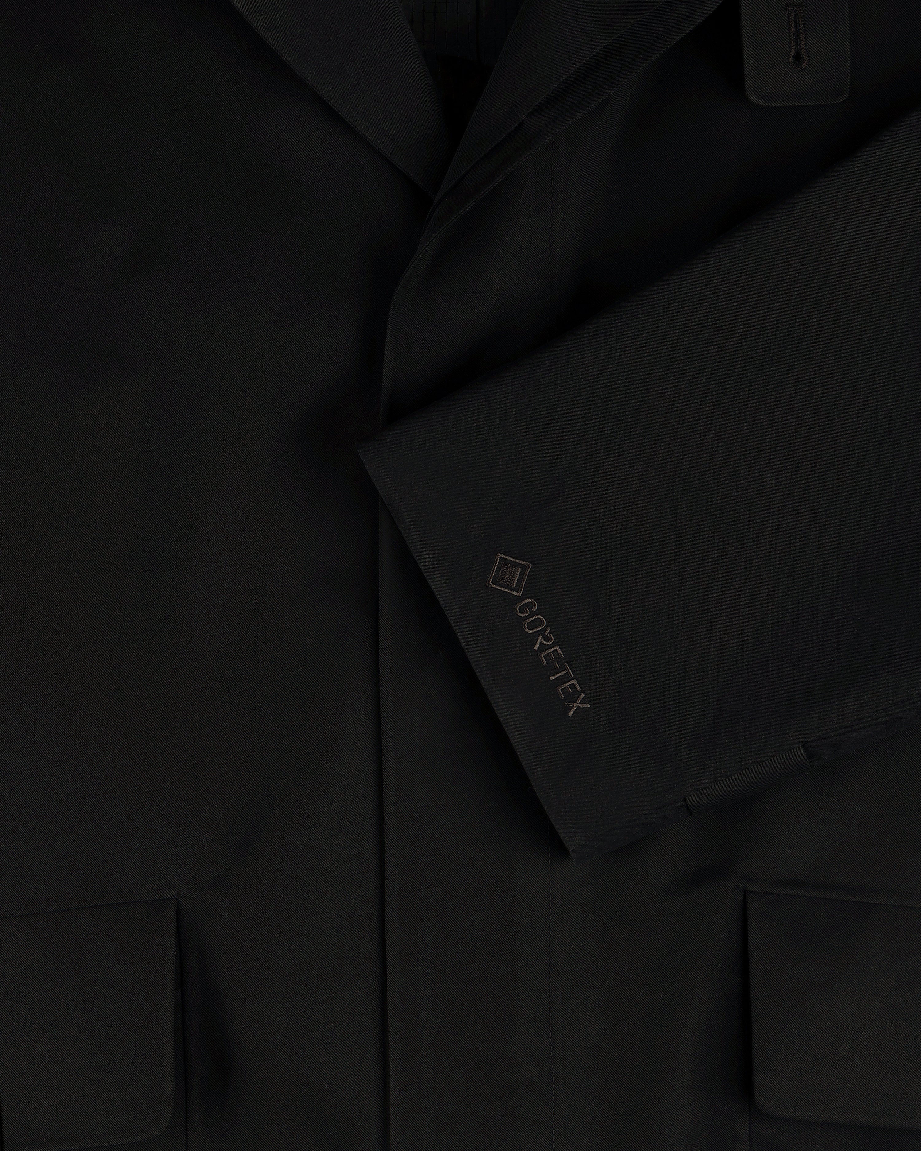 Close-up of the GORE-TEX Balmacaan Coat sleeve with embroidered logo and lower pockets visible.