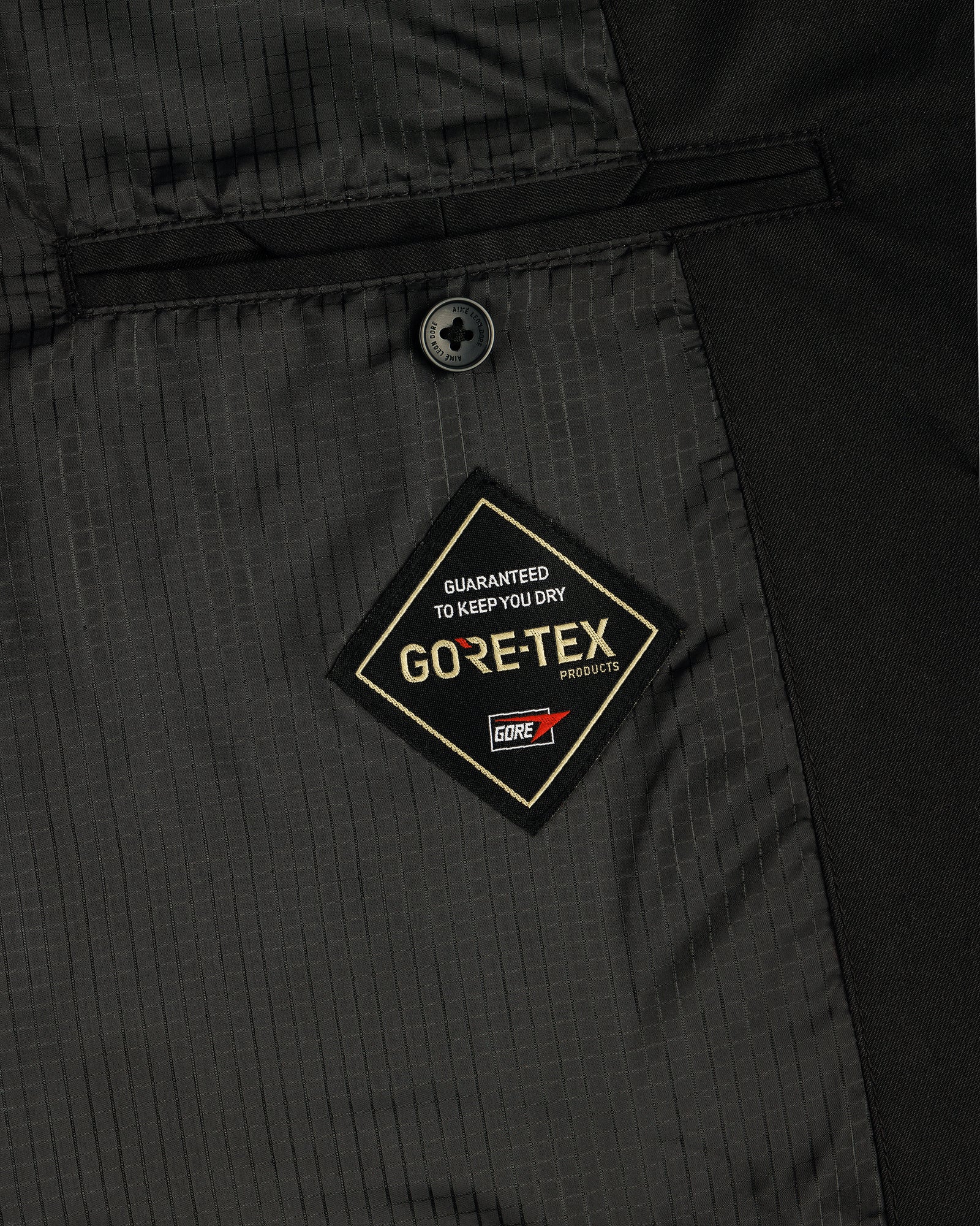 Close-up of the GORE-TEX Balmacaan Coat’s inside pocket featuring a GORE-TEX label and a single black button above it.